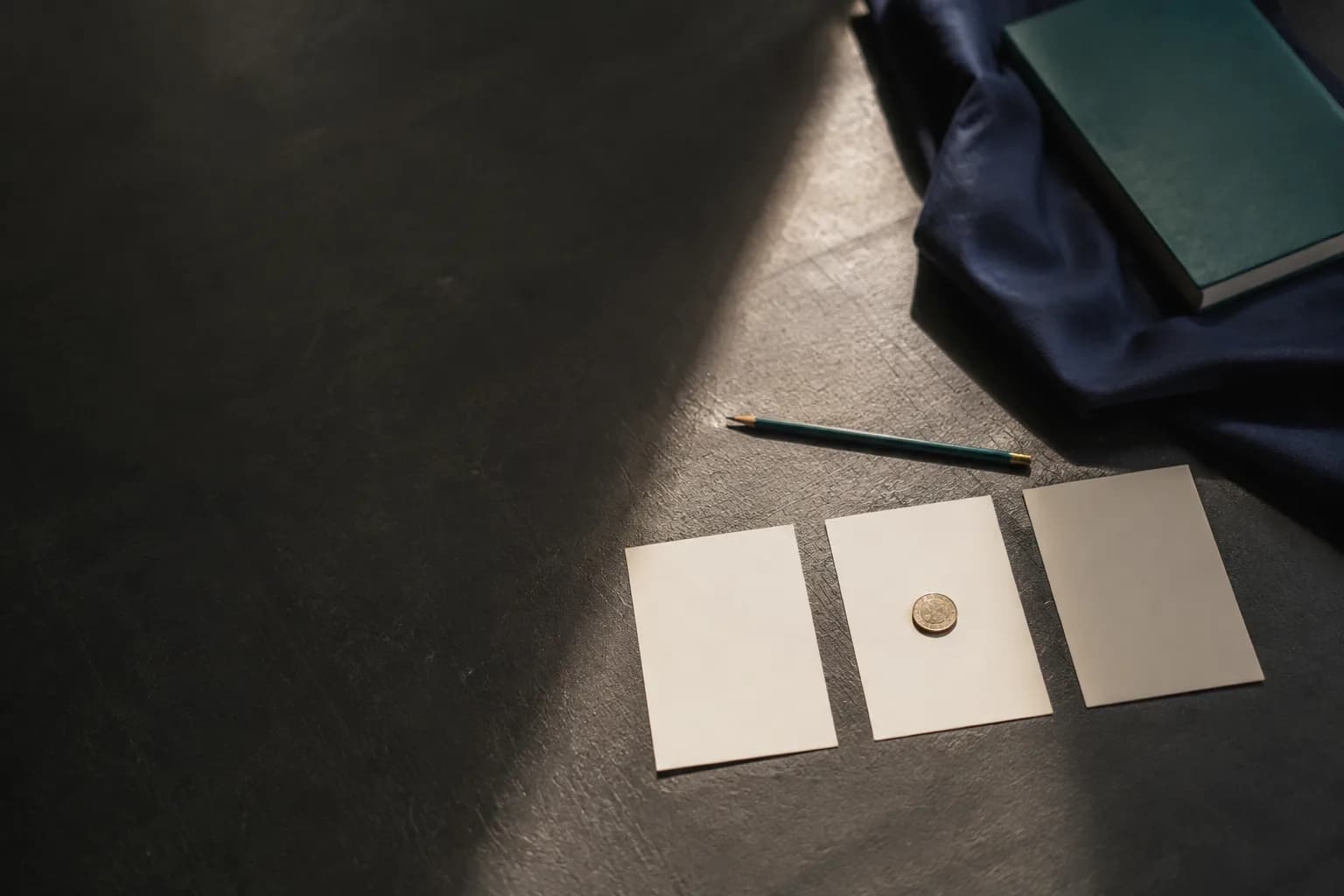 Three index cards laid on a table with a single coin placed on the middle one
