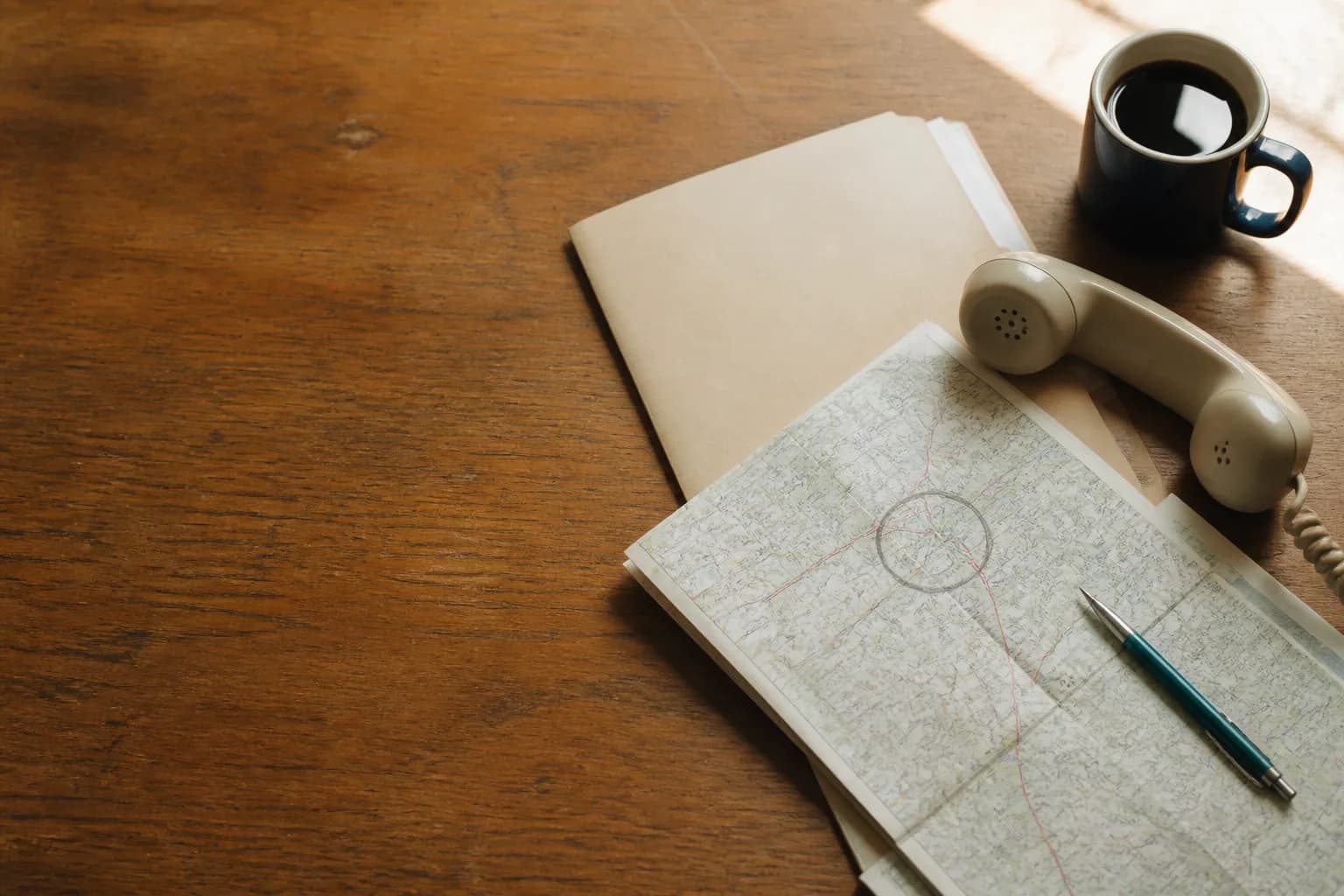A desk with a policy folder, a printed map with a drawn radius, and a phone on a wooden surface