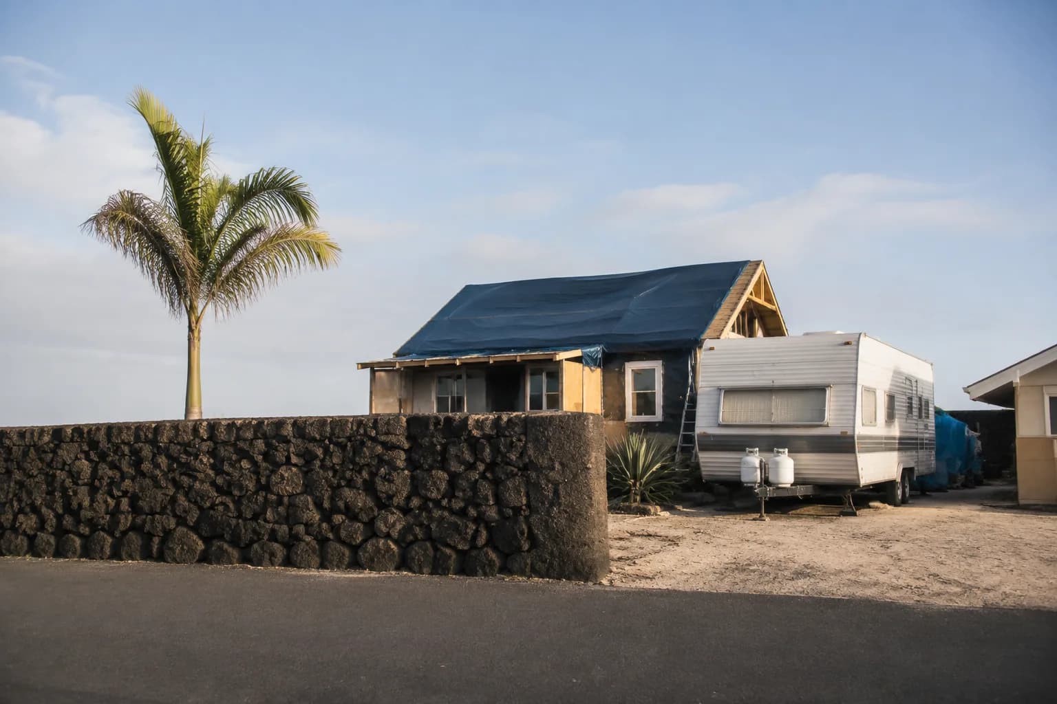 A residential driveway with a travel trailer in regional terrain, no landmarks