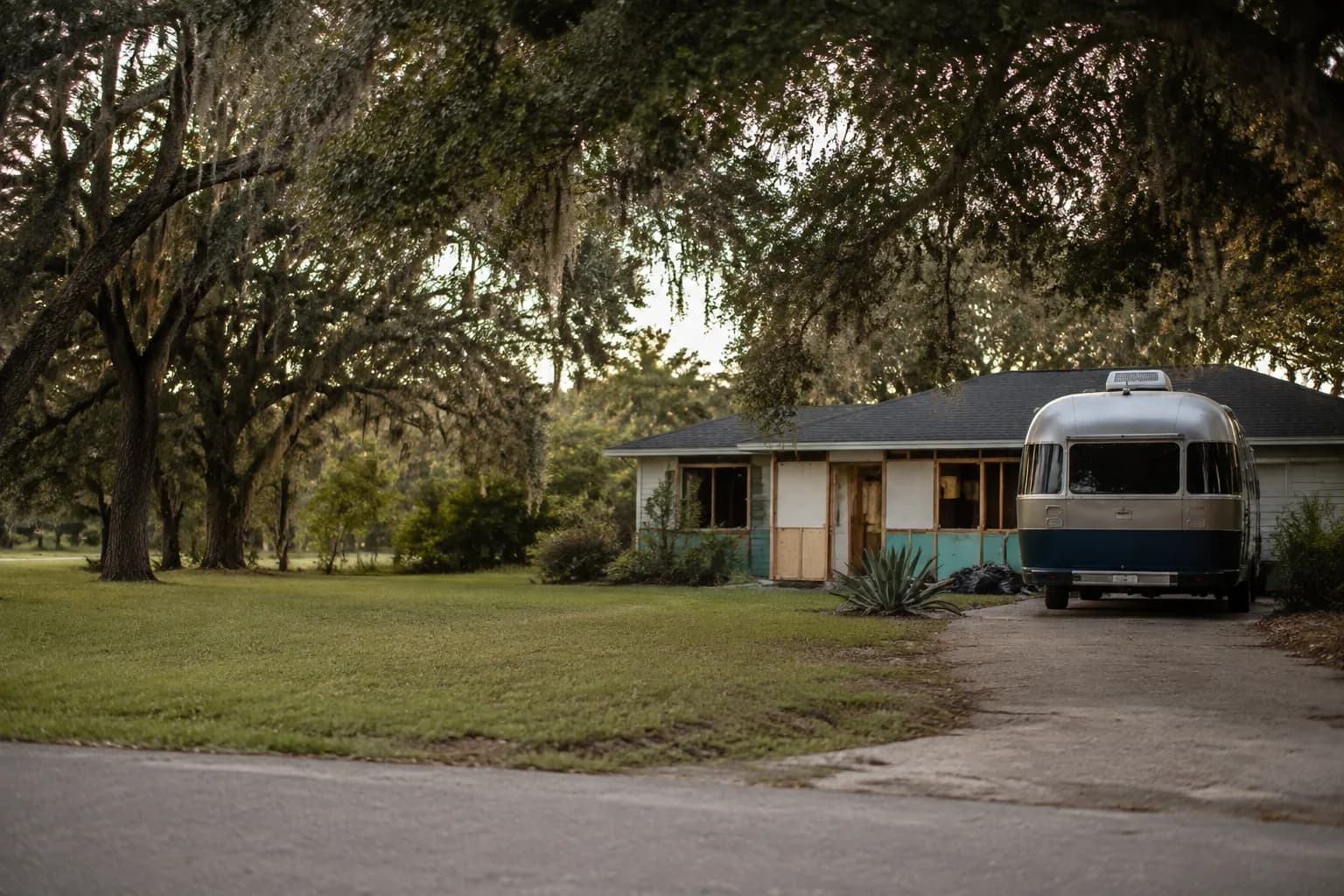 A residential driveway with a travel trailer in regional terrain, no landmarks